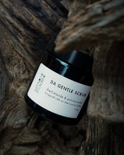 A natural coffee body scrub displayed outdoors with a forest background, showcasing its eco-friendly ingredients.